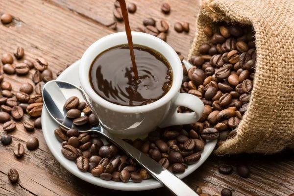 Cup of coffee surrounded by coffee beans.